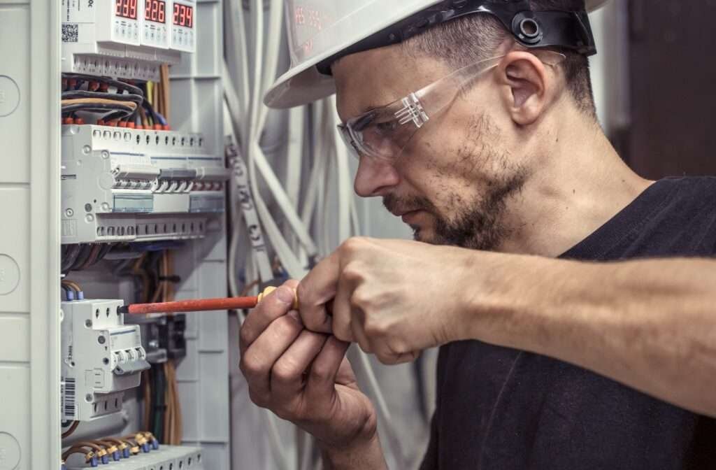 a male electrician works in a switchboard with an electrical connecting cable