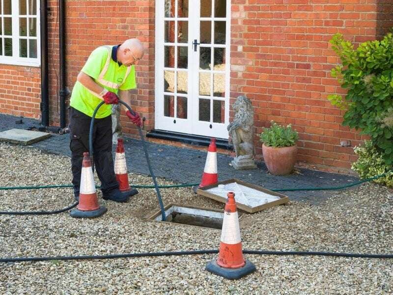 Man Jetting Sewage Drain Outside House 800x600
